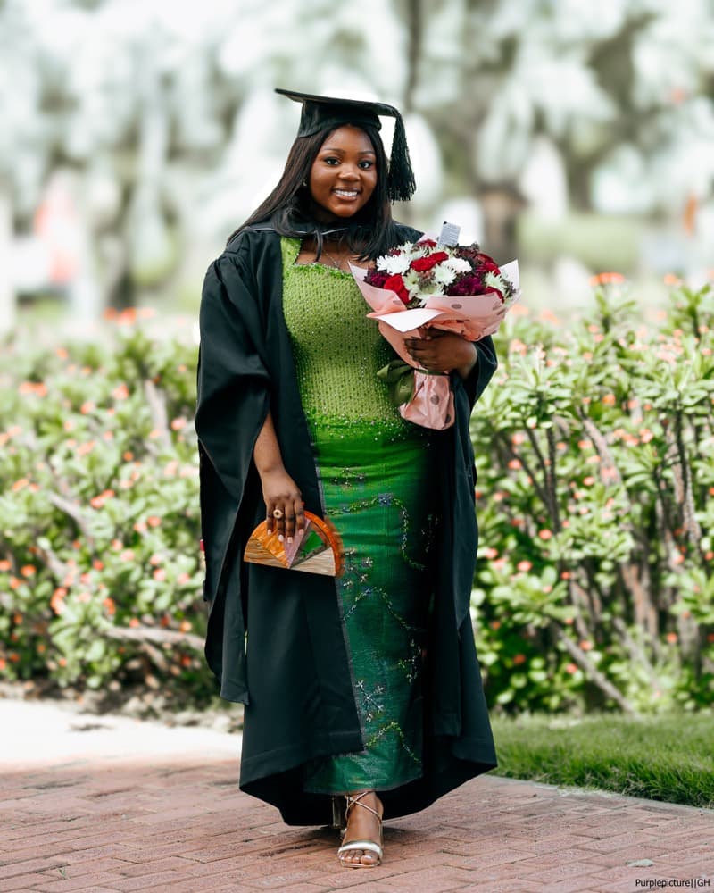 Graduate in a black gown holding a bouquet
