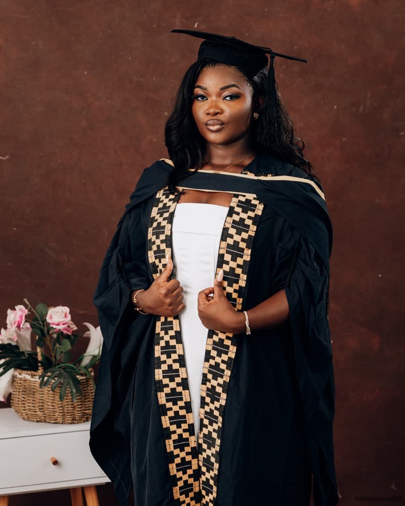 Graduate in a black gown with kente facing