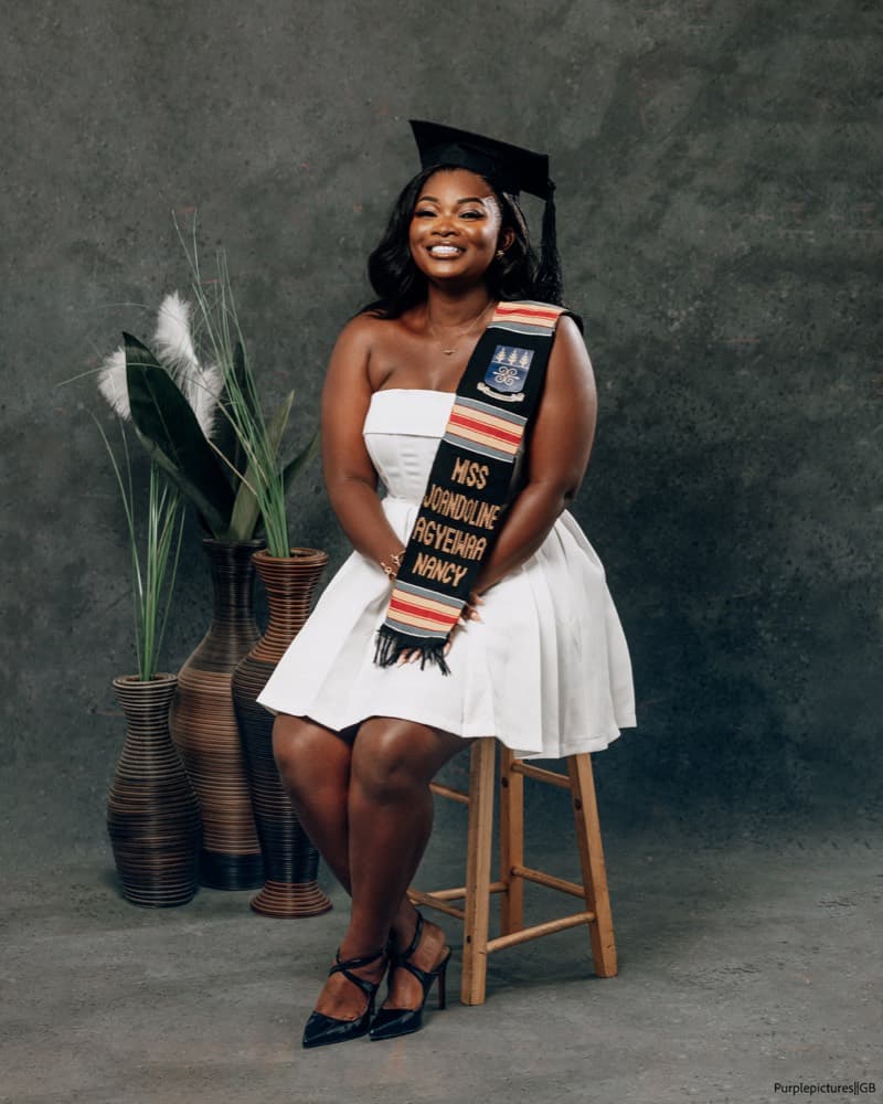 Graduate seated in a white dress and mortarboard